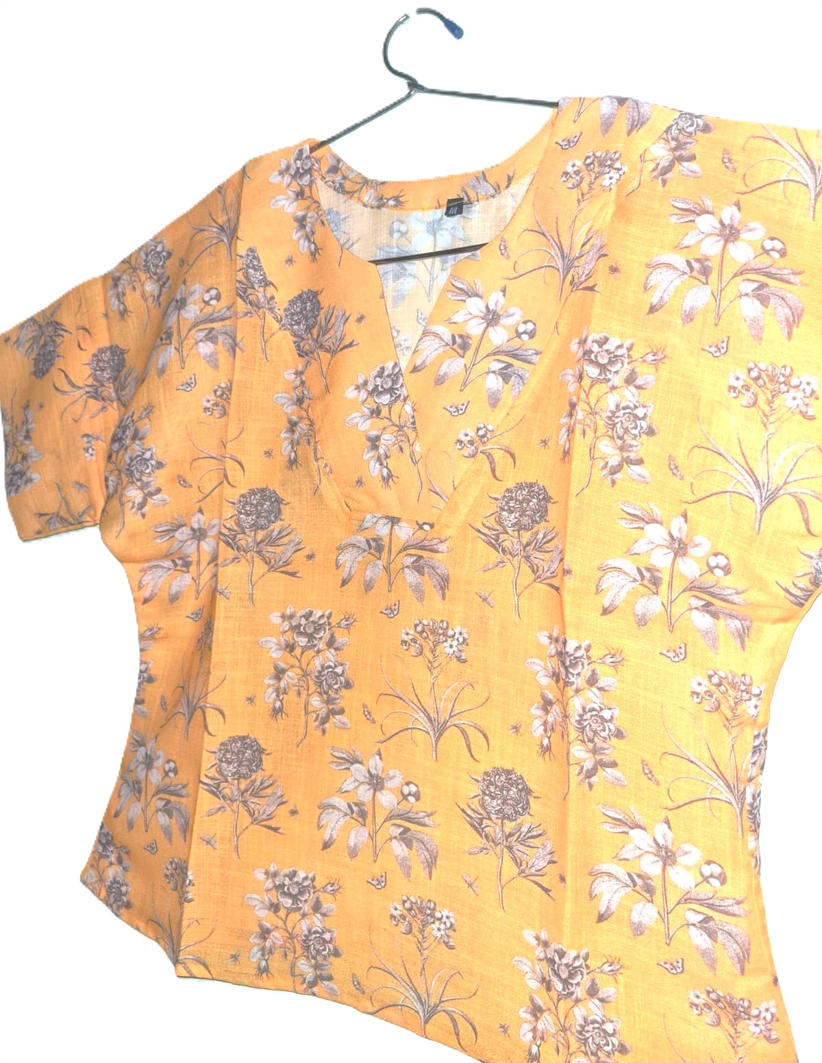 Yellow floral blouse on a hanger against a white background